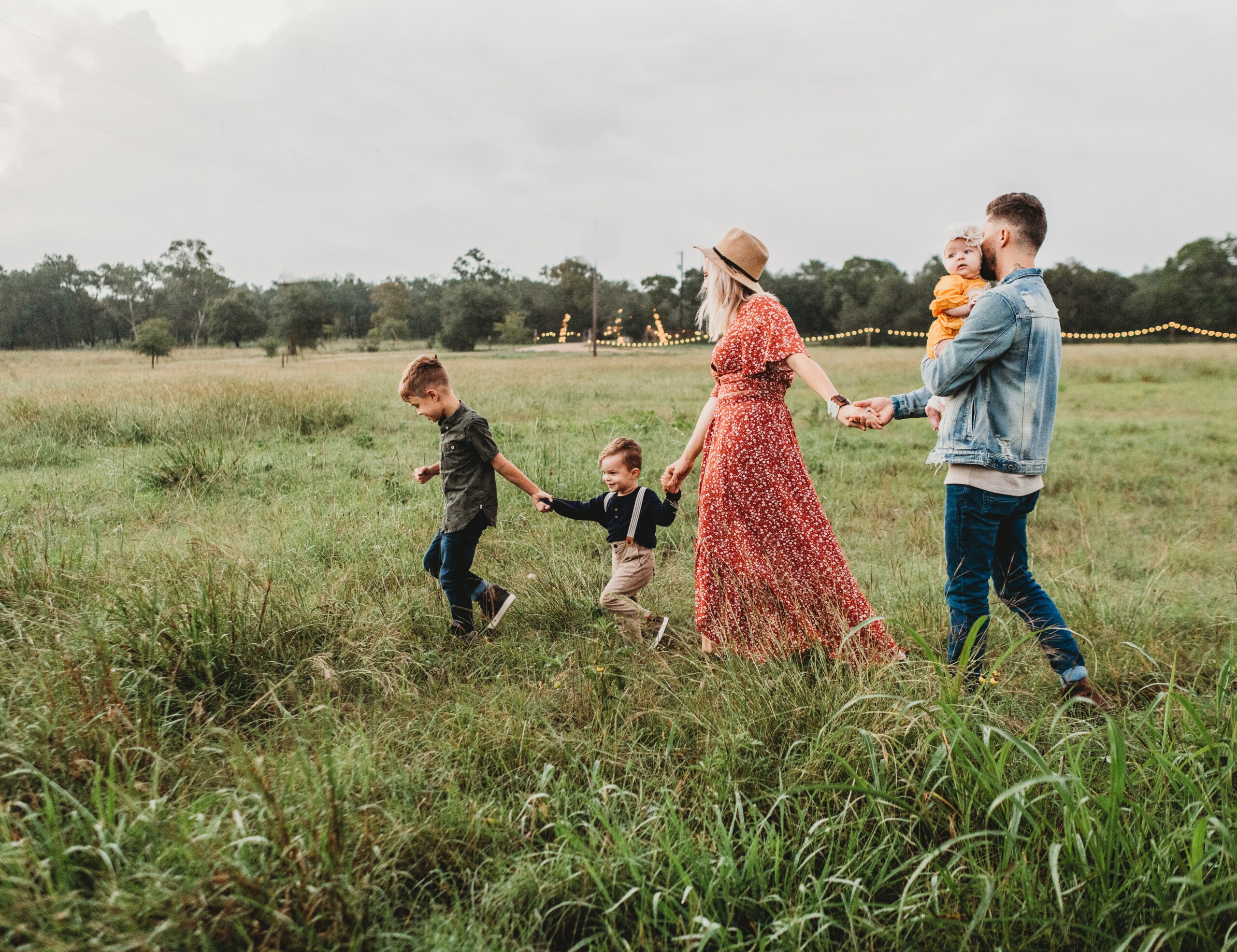 jessica-rockowitz-5NLCaz2wJXE-unsplash young family of 3 children and two parents walking through a field.