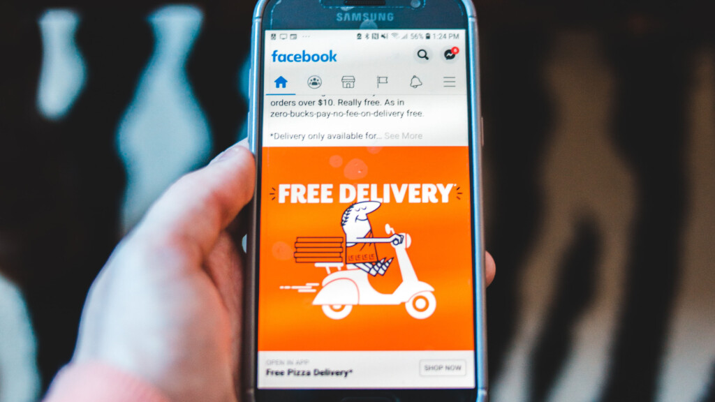 Smarphone in hand with Facebook ad of Free Pizza Delivery