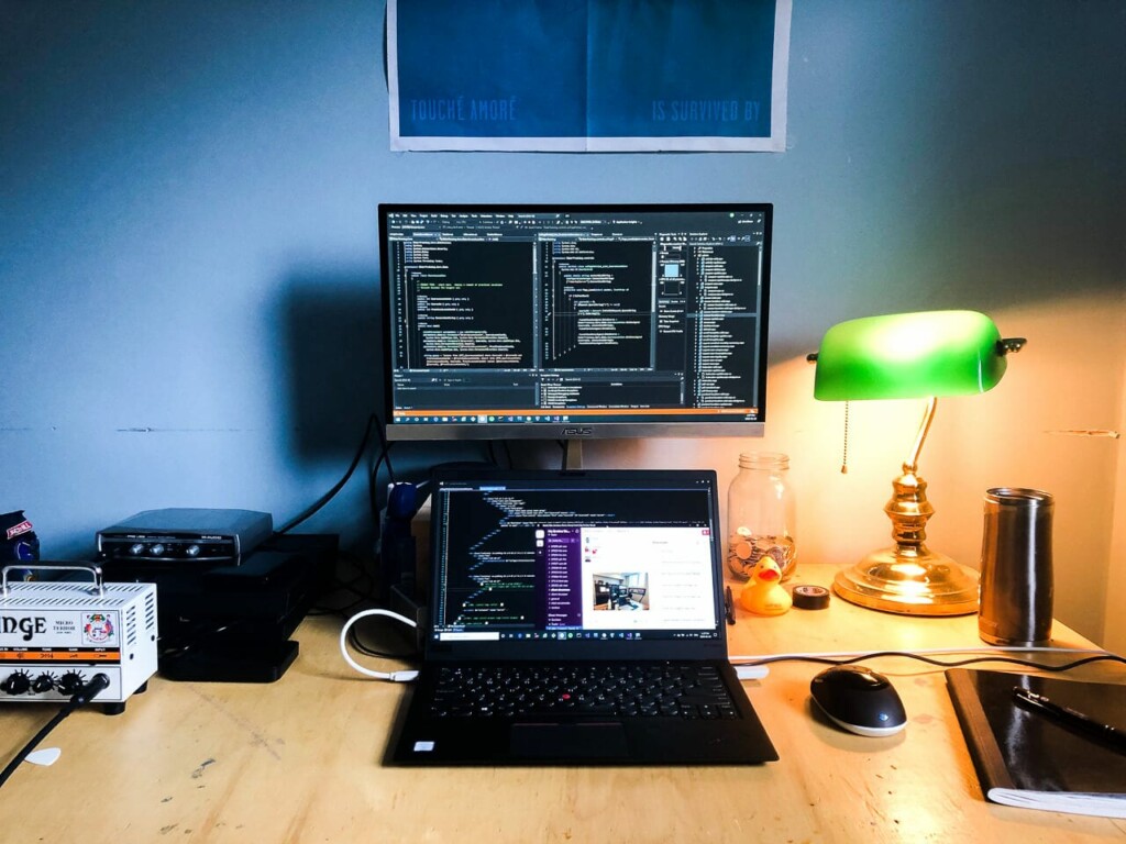 laptop on a desk with a second monitor on the wall