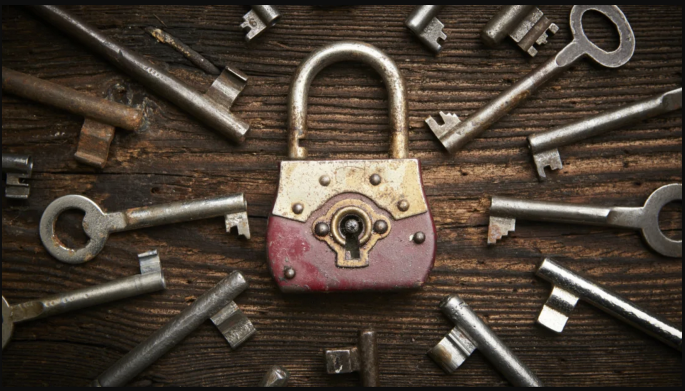 wooden table with old lock in center, surrounded by old skeleton style keys