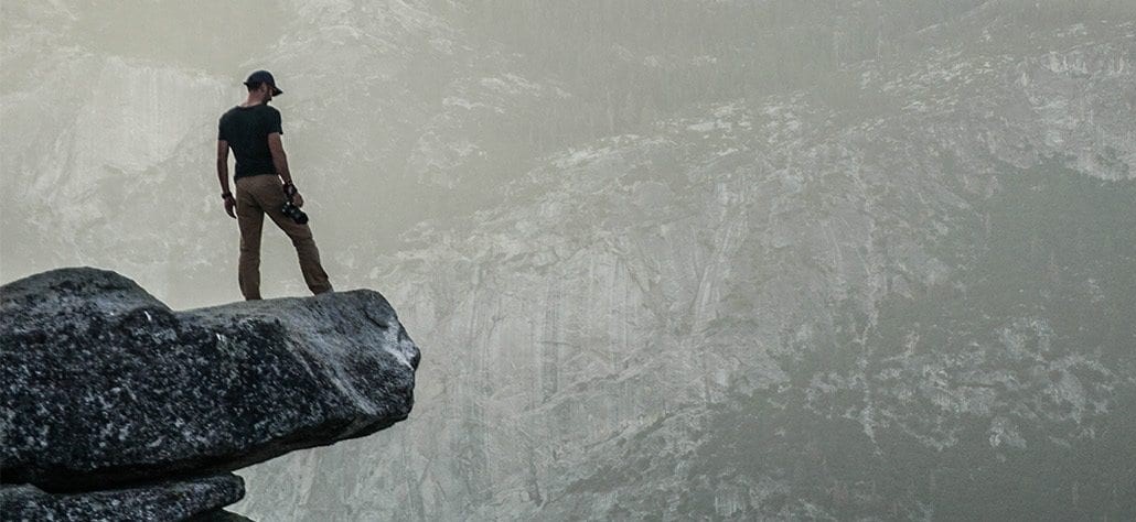 Person standing on the edge of a mountain cliff