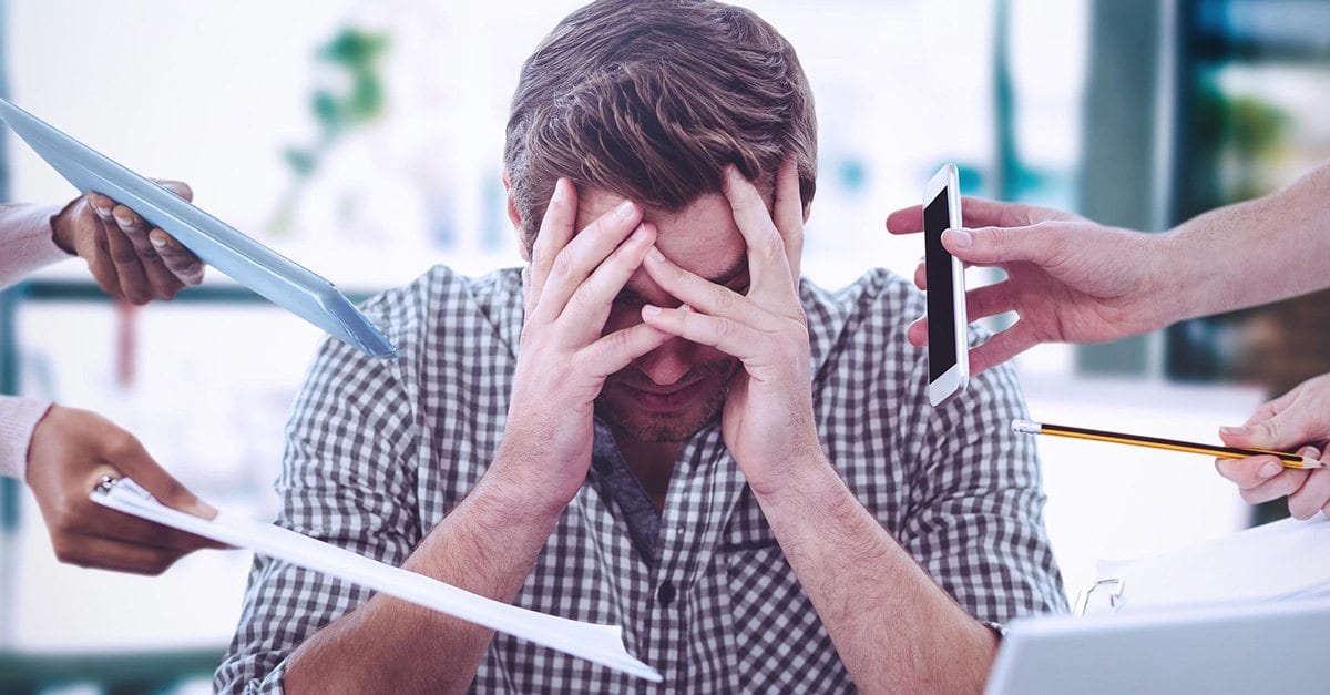 Person with head in their hands while 4 different hands are trying to hand him work items.