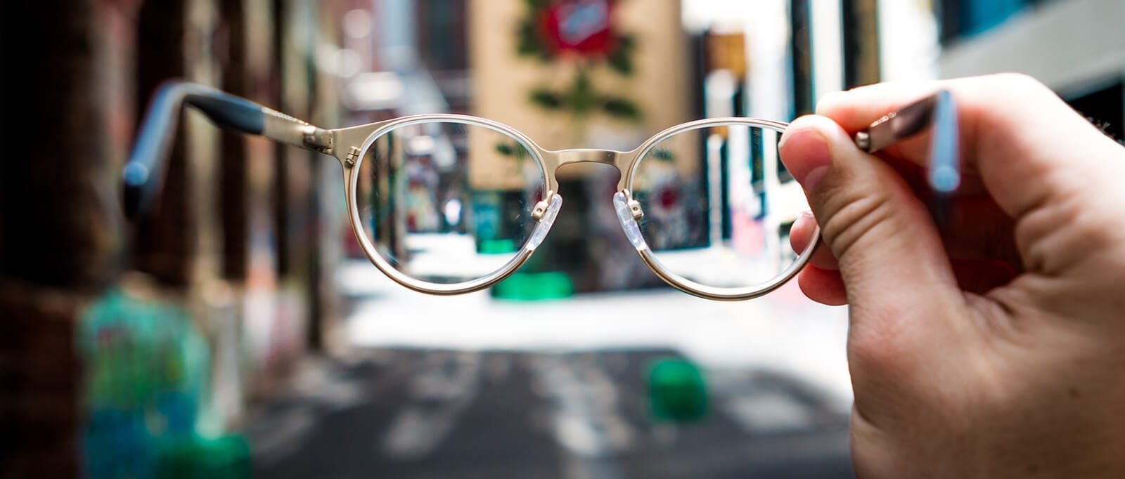 Pair of glasses held out in front of the camera - allowing focus of the street.