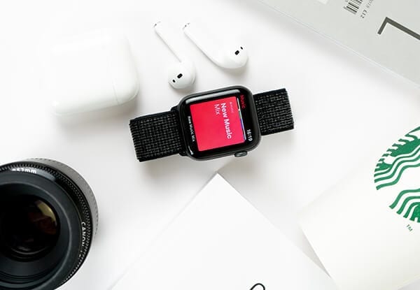 black apple watch and white airpods sitting on a white table