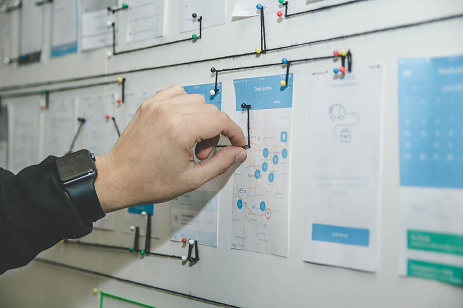 man's hand putting a thumbtack on a board filled with images