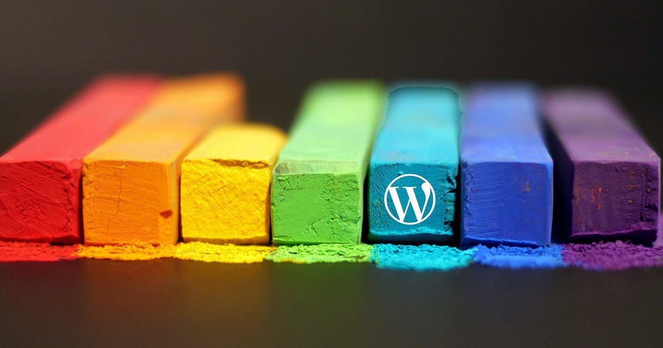 Rainbow colours of Chalk with a Wordpress logo on the end of one.