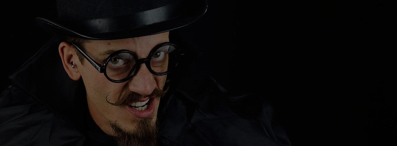 Dark image of creepy looking male, thick glasses, dark hair and gotee