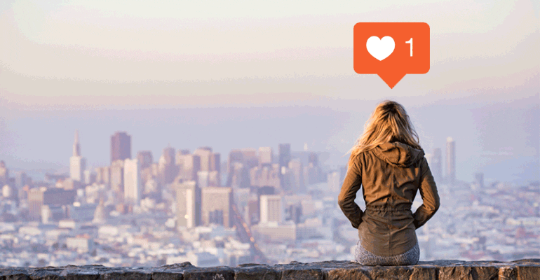 woman sitting on a rock ledge, looking out over a city skyline with a like counter graphic over her head