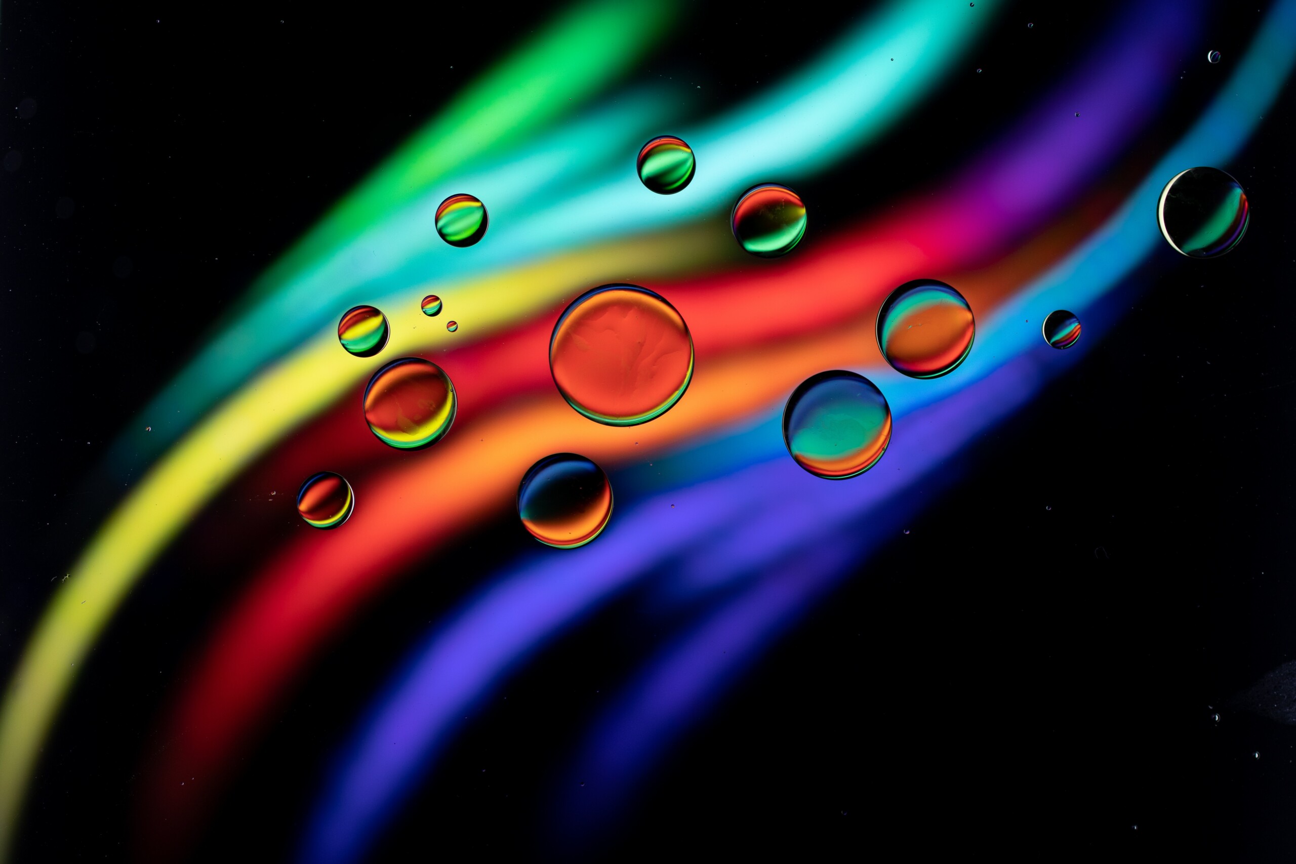 bright color swooshes on black background with water droplets on top