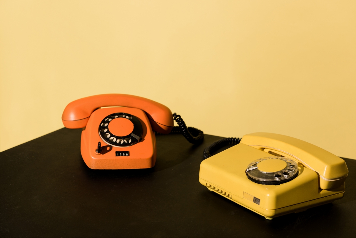 two old telephones on black table on yellow background