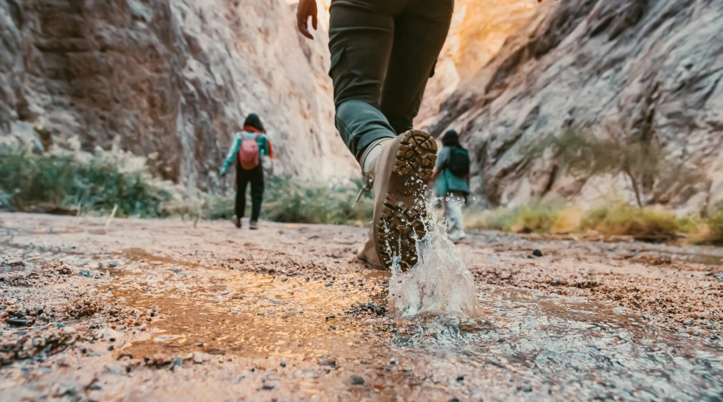Womans feet in boots walking through river splashing water up