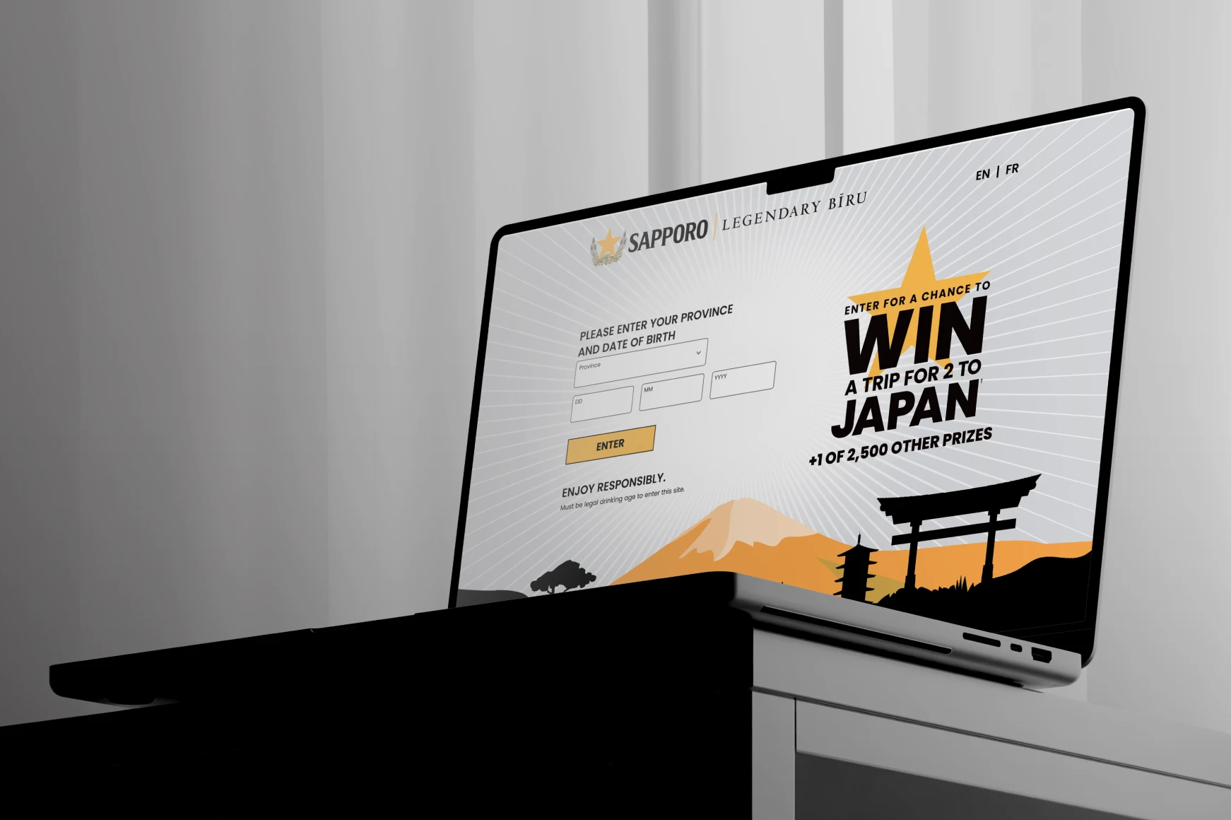 Laptop on table with curtains behind it showing the digital development of Contest Website.